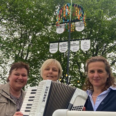 Auf dem M&uuml;hlenberg h&auml;ngten (v. l.) Monika Bertenhoff, Sonja Wesseling und Nicole Gebhard die Wappen unter den bunten Maikranz.